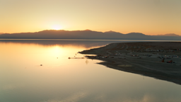 Glassy waters mirror a golden sunset over Bombay Beach and the Salton Sea's quiet, desolate shores.