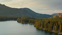 Evergreen forests embrace the still waters of Lake Mary beneath golden Sierra Nevada peaks.