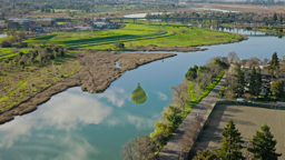 Calm waters mirror the sky above Napa's vineyard-lined wetlands and rolling green countryside.
