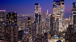 Glittering towers illuminate the Manhattan skyline as twilight surrenders to night.