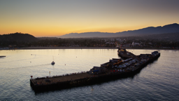 Santa Barbara's historic pier extends into the golden harbor as the sun dips behind the coastal mountains.