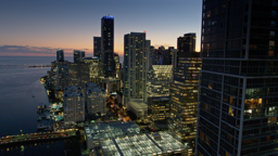 Glass towers of Miami's financial district glow against a deep twilight sky over Biscayne Bay.