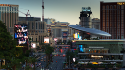 Neon signs and resort towers line the glittering expanse of the Las Vegas Strip at dusk.
